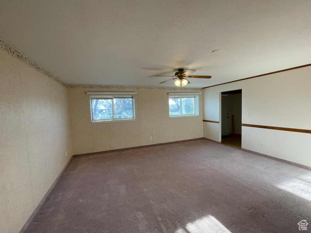 Carpeted empty room featuring baseboards and a ceiling fan