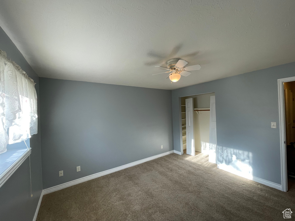 Unfurnished bedroom with a closet, carpet flooring, baseboards, and a ceiling fan