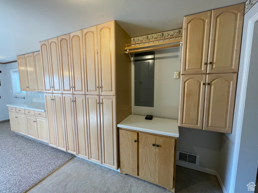 Interior space featuring visible vents, baseboards, electric panel, light countertops, and light brown cabinetry