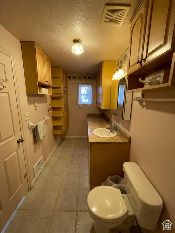 Bathroom featuring visible vents, toilet, vanity, and tile patterned flooring