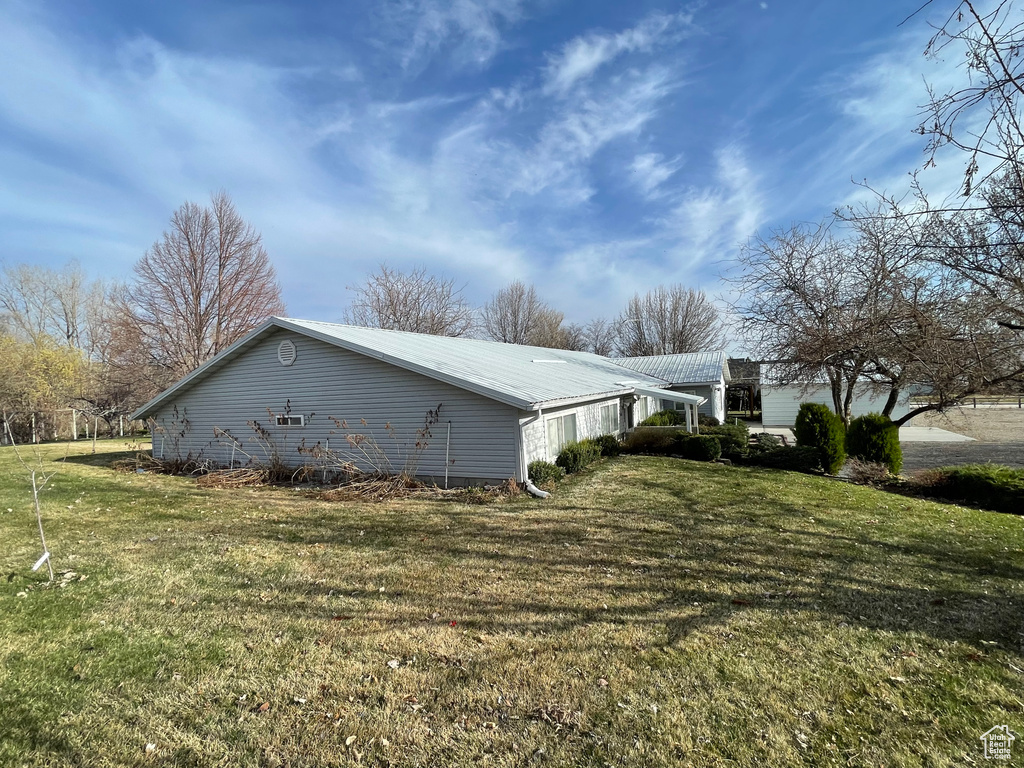 View of side of property with a yard and metal roof