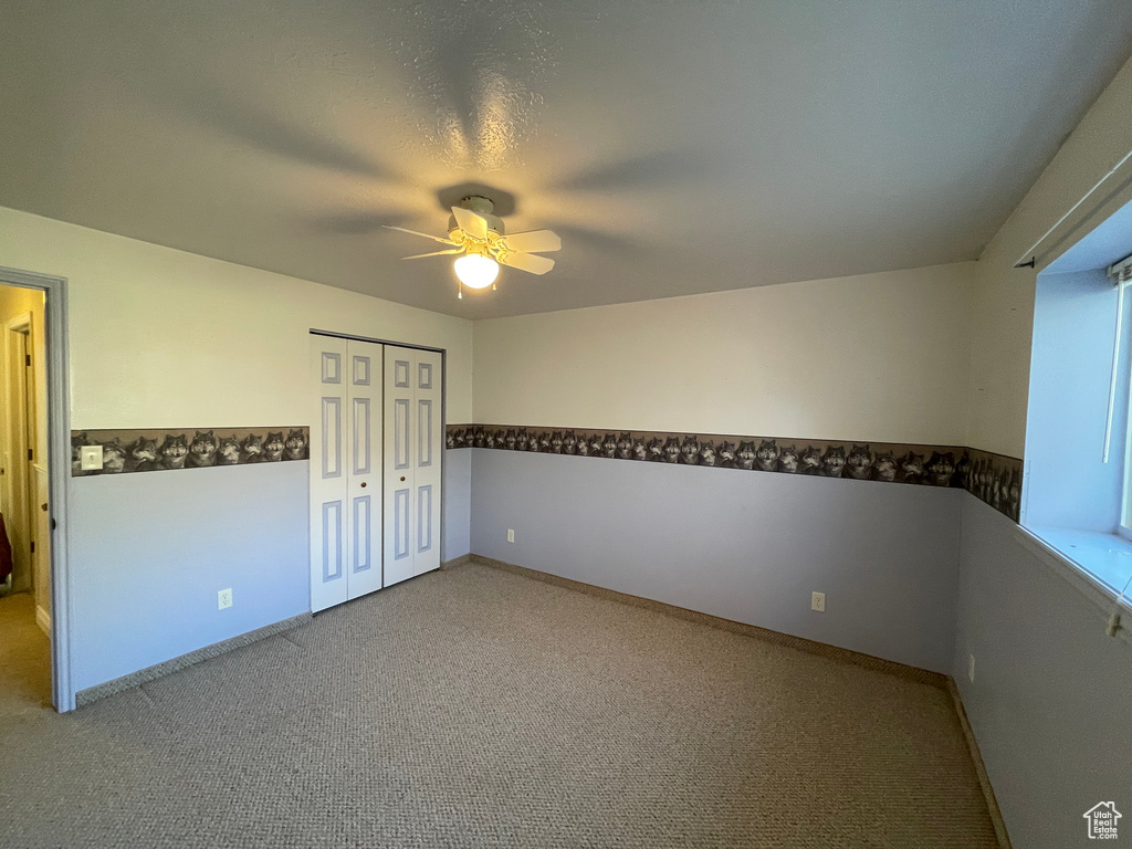 Unfurnished bedroom with carpet, a closet, and ceiling fan