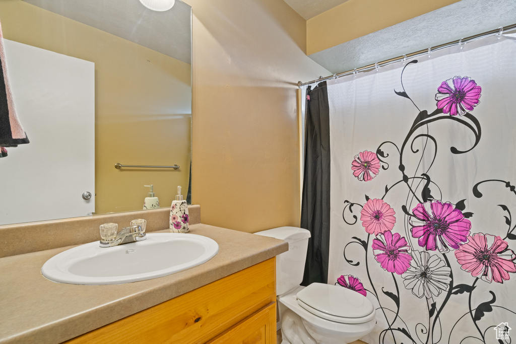 Bathroom with toilet, curtained shower, and vanity