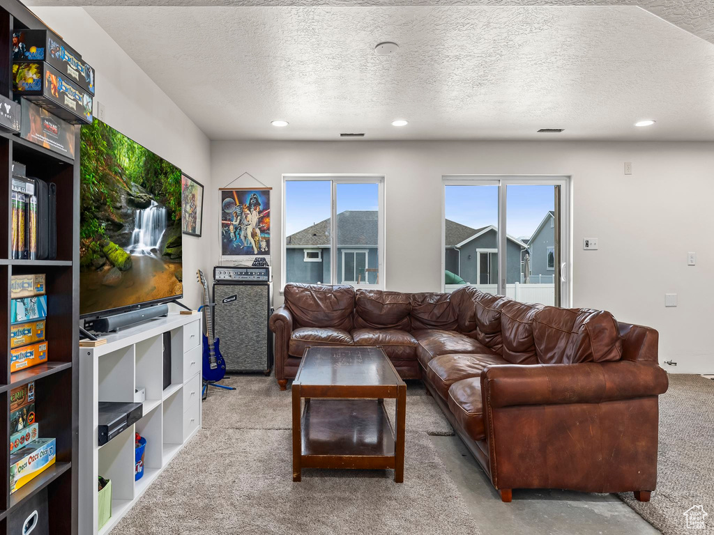 Carpeted living area featuring a textured ceiling and recessed lighting