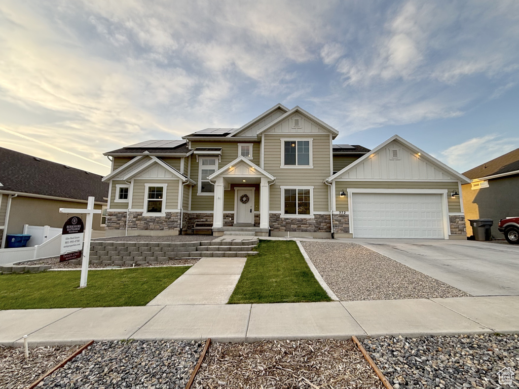 Craftsman inspired home featuring stone siding, board and batten siding, a garage, and concrete driveway