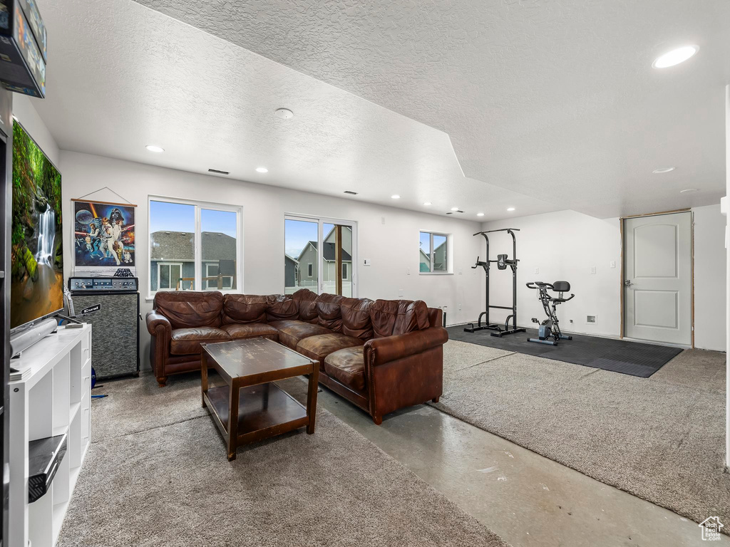 Living room with recessed lighting, a textured ceiling, and finished concrete flooring