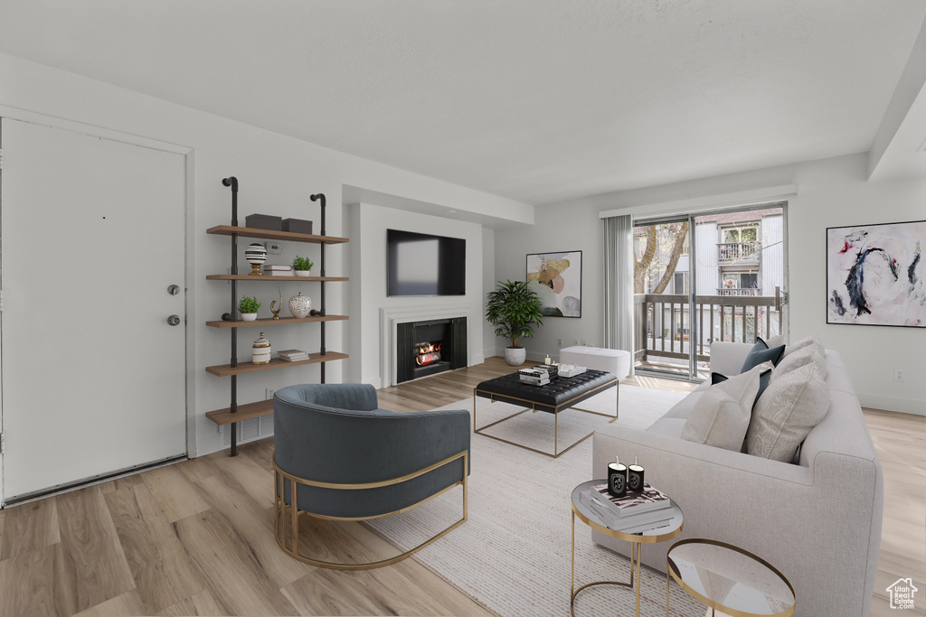 Living area with light wood-type flooring and a warm lit fireplace