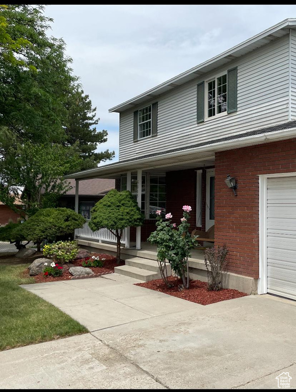 Traditional-style home featuring a porch, a garage, and brick siding