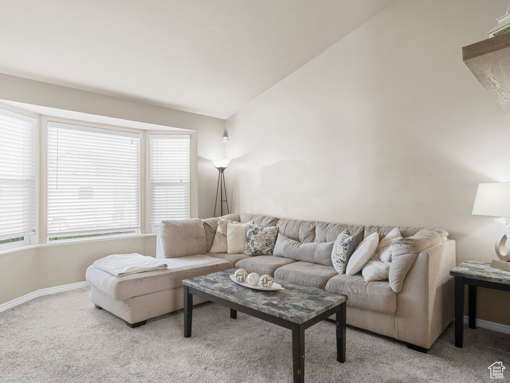 Carpeted living room with baseboards and lofted ceiling