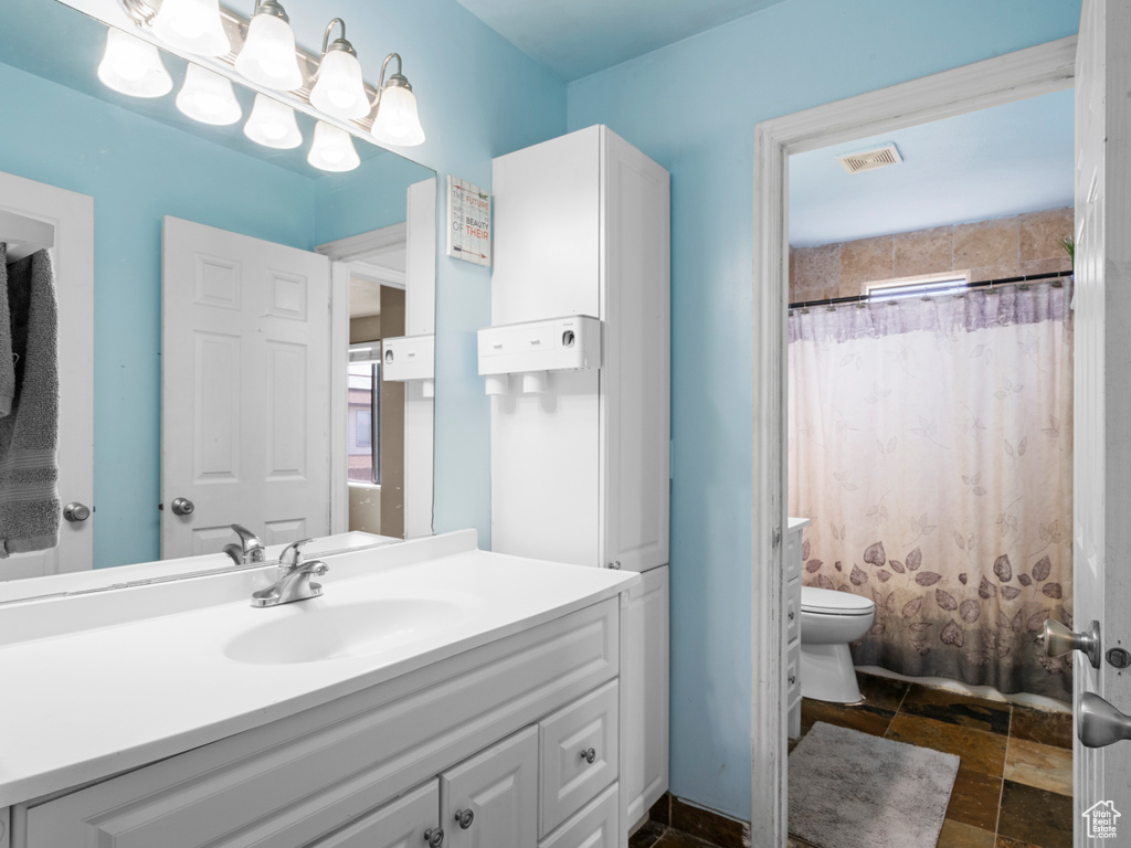 Bathroom featuring toilet, vanity, and stone tile floors