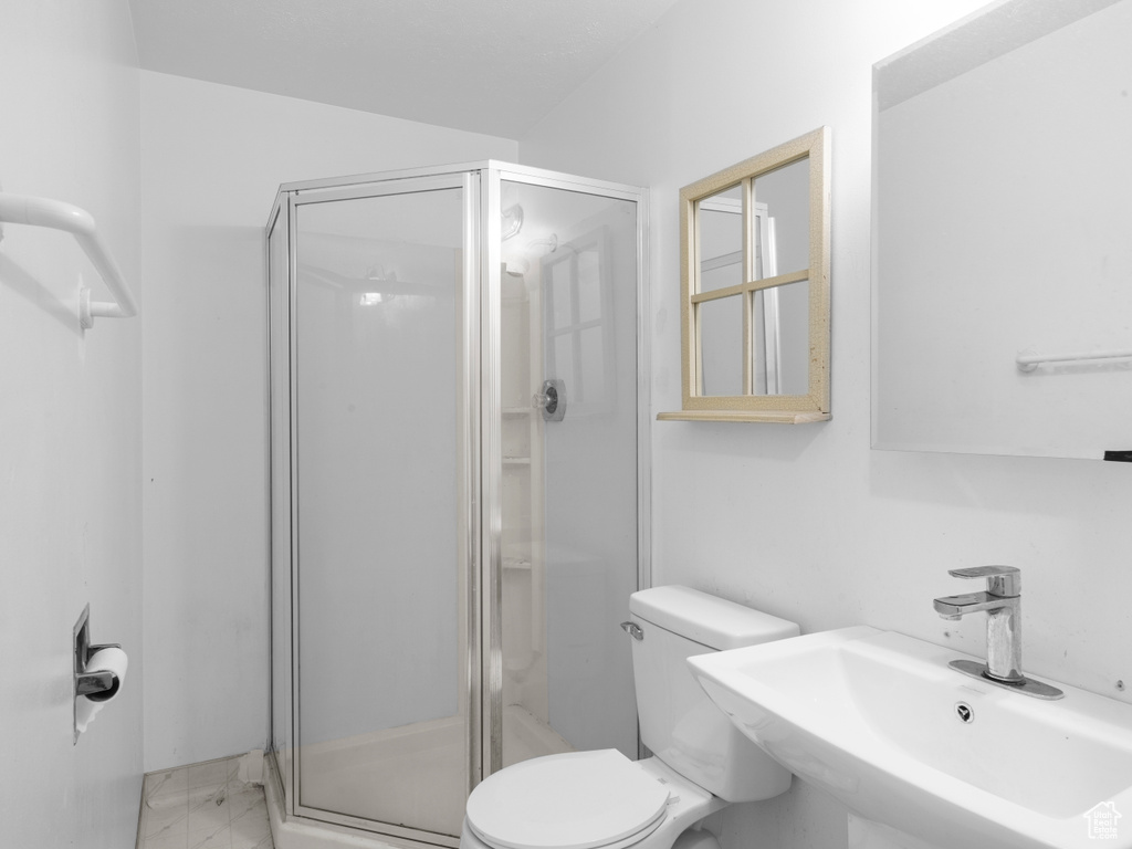 Full bathroom featuring a sink, toilet, a shower stall, and marble finish floor