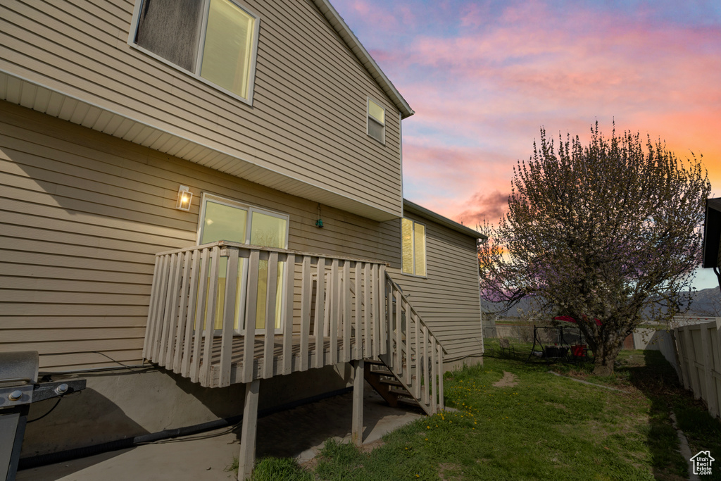 View of property exterior with a fenced backyard, a deck, and a lawn