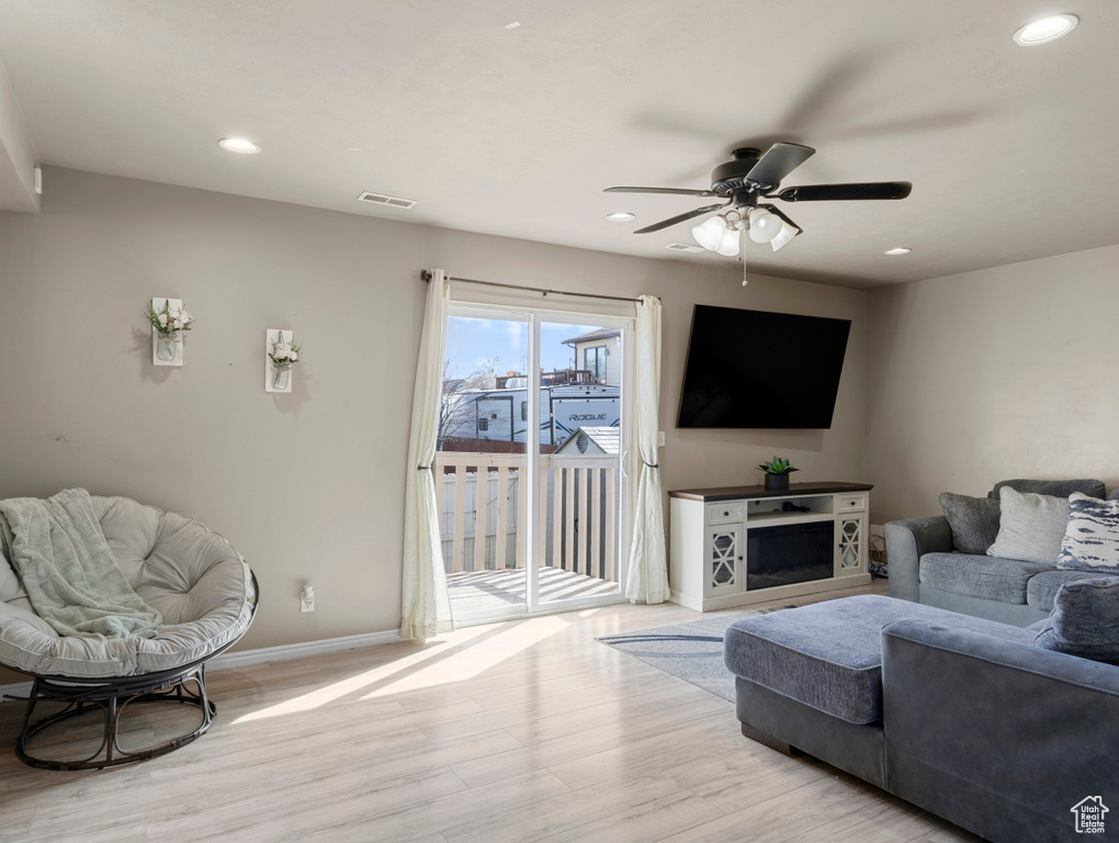 Living room with light wood finished floors, ceiling fan, baseboards, and recessed lighting