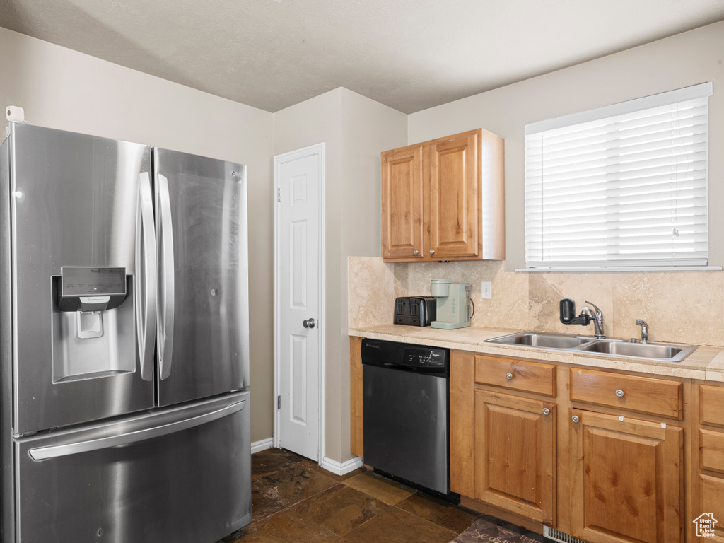 Kitchen with stainless steel fridge with ice dispenser, baseboards, dishwasher, a sink, and light countertops