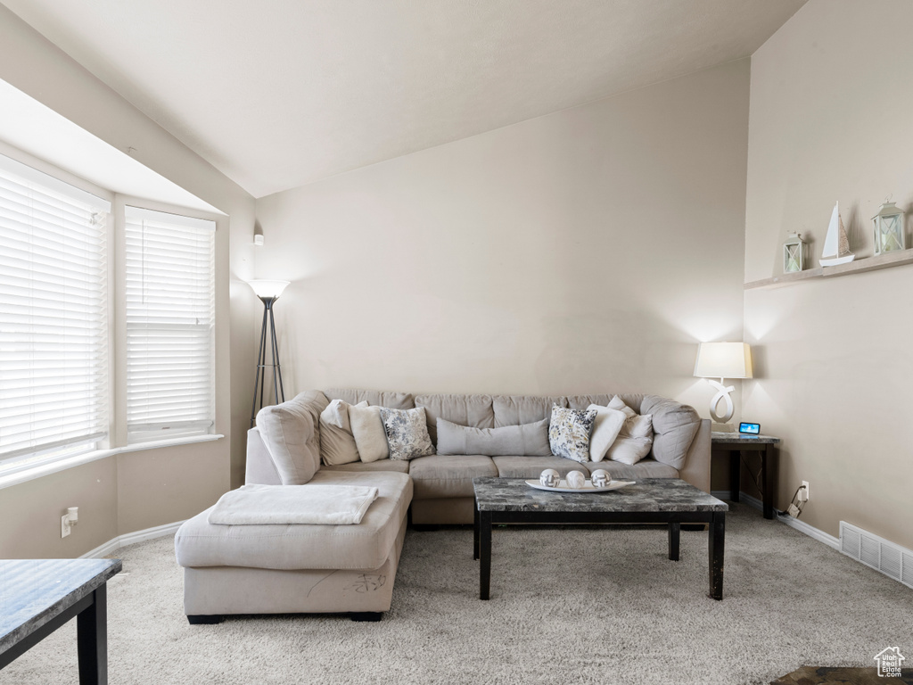 Carpeted living room featuring visible vents, a wealth of natural light, and lofted ceiling
