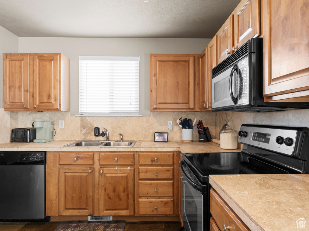 Kitchen with dishwashing machine, black microwave, light countertops, a sink, and stainless steel electric range