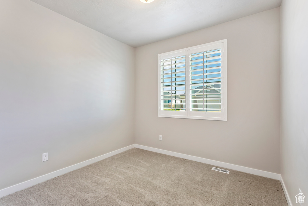 Carpeted spare room featuring visible vents and baseboards