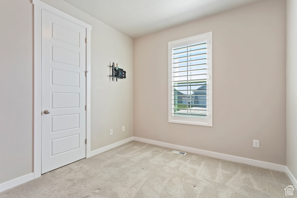 Unfurnished room with visible vents, light colored carpet, and baseboards