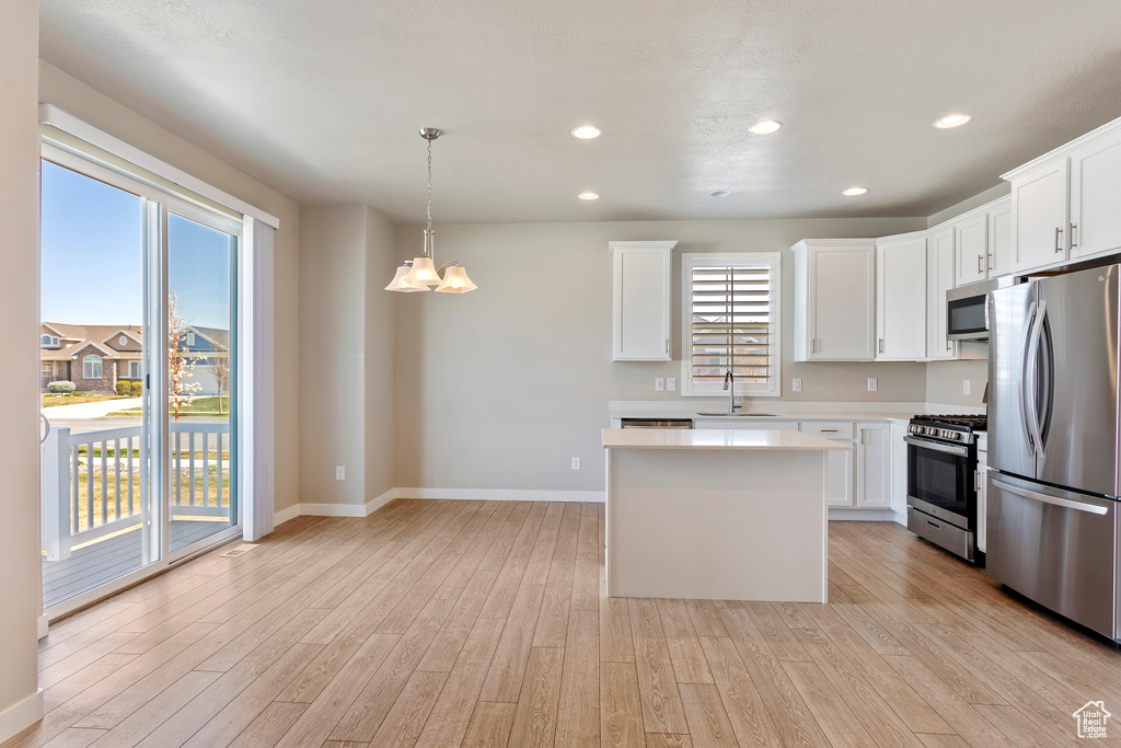 Kitchen with stainless steel appliances, light wood-style flooring, light countertops, and baseboards