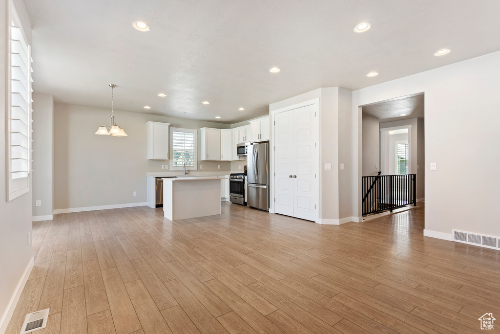 Unfurnished living room with visible vents, light wood-type flooring, and baseboards