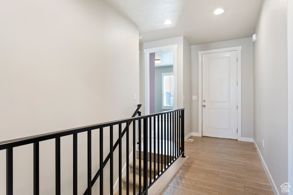 Hall with light wood-style floors, baseboards, an upstairs landing, and recessed lighting