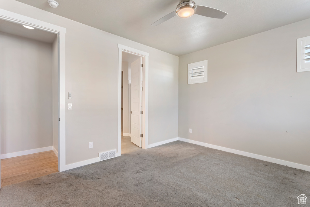 Empty room with carpet flooring, baseboards, a ceiling fan, and visible vents