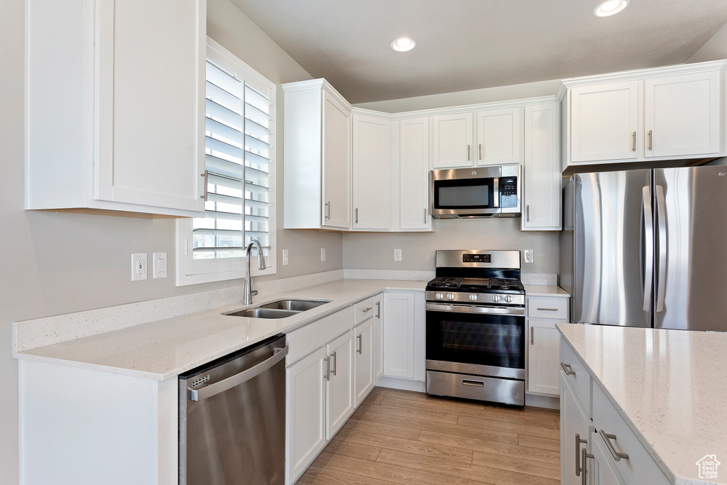Kitchen featuring white cabinets, recessed lighting, a sink, stainless steel appliances, and light wood finished floors