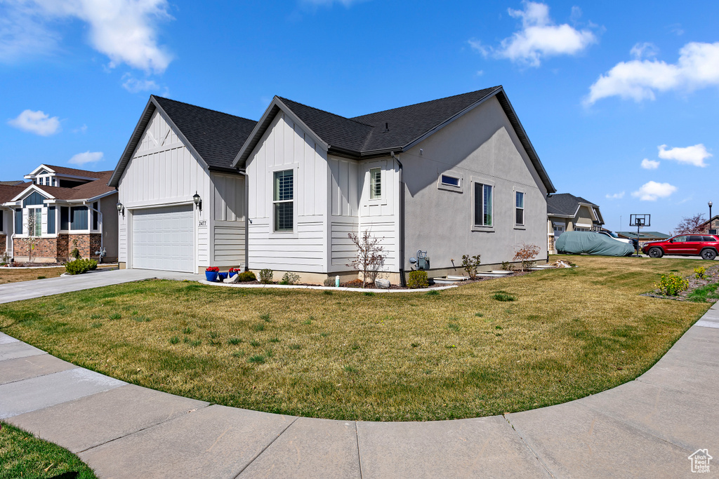 Modern inspired farmhouse with concrete driveway, board and batten siding, a garage, and a front lawn