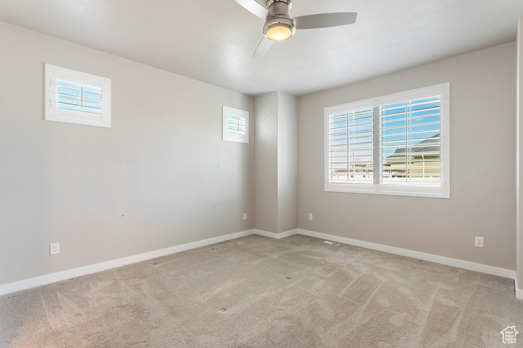 Carpeted empty room with ceiling fan and baseboards