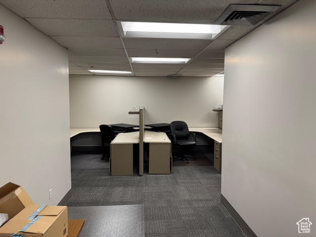 Home office featuring dark colored carpet, a paneled ceiling, and visible vents