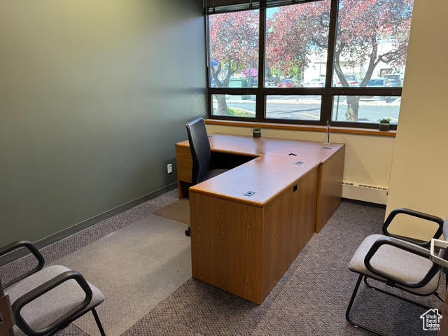 Carpeted office space with a baseboard radiator