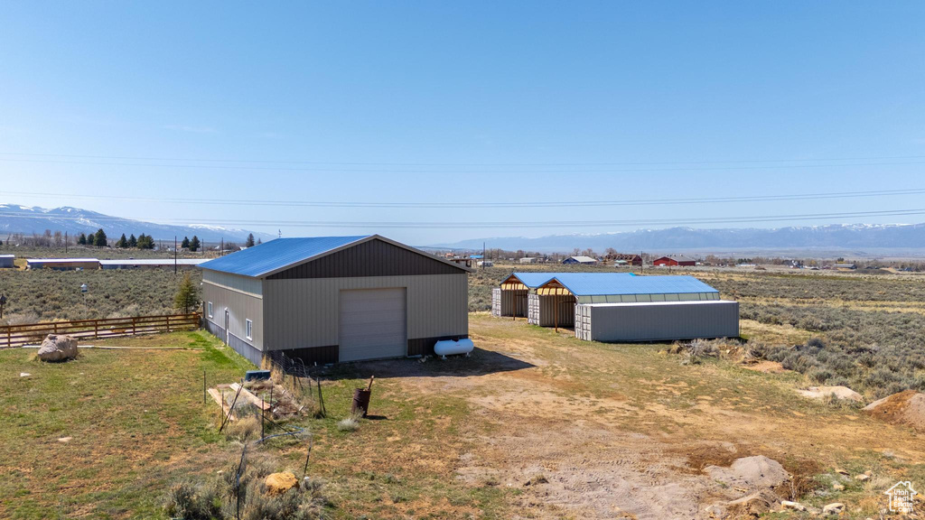 View of pole building featuring a mountain view, driveway, and fence