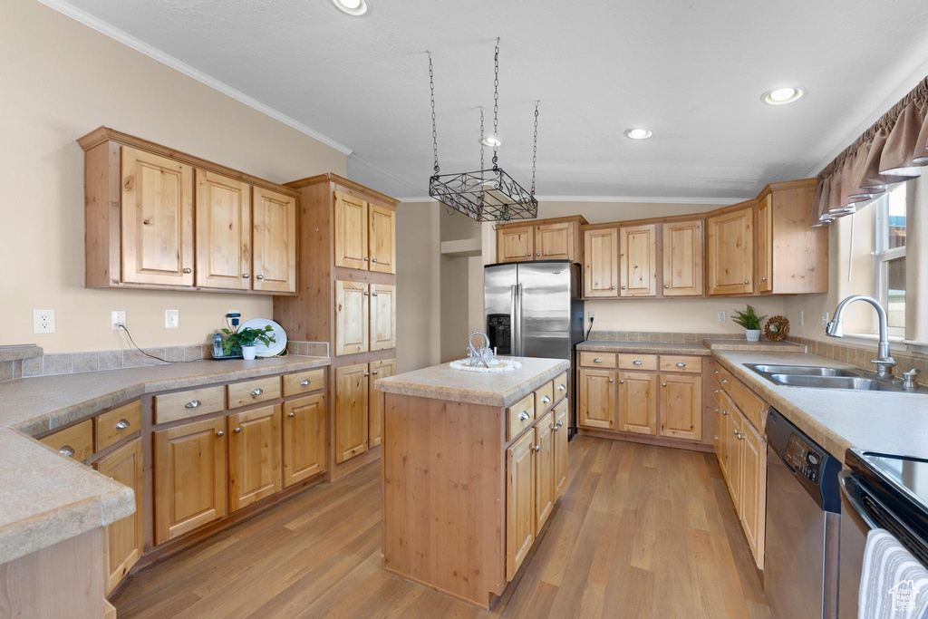 Kitchen with light wood-style flooring, ornamental molding, light countertops, a sink, and stainless steel appliances