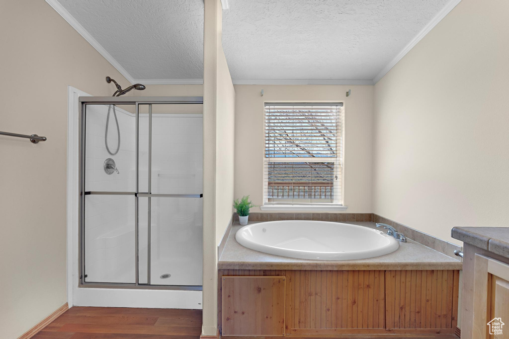 Full bath featuring ornamental molding, a textured ceiling, a shower stall, wood finished floors, and a garden tub