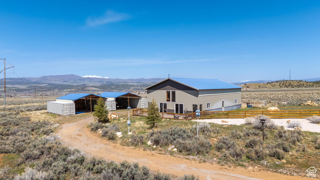 Rear view of property with an outbuilding, a mountain view, a pole building, and fence