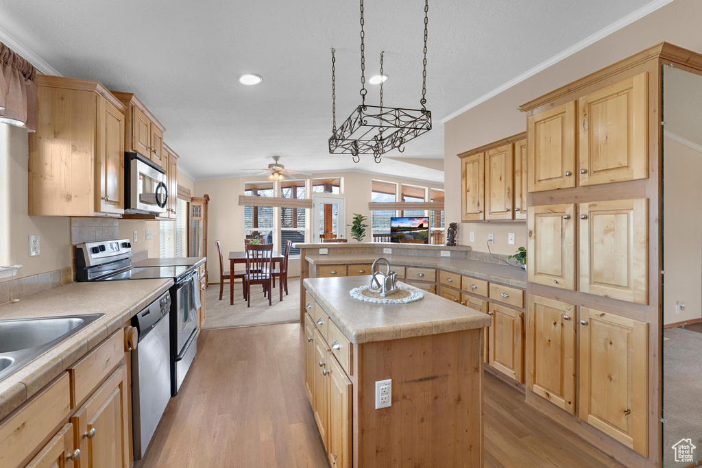 Kitchen with light countertops, light brown cabinets, appliances with stainless steel finishes, and ceiling fan