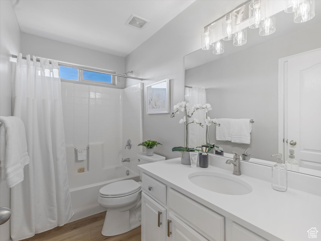Bathroom featuring shower / bath combo, visible vents, toilet, vanity, and wood finished floors