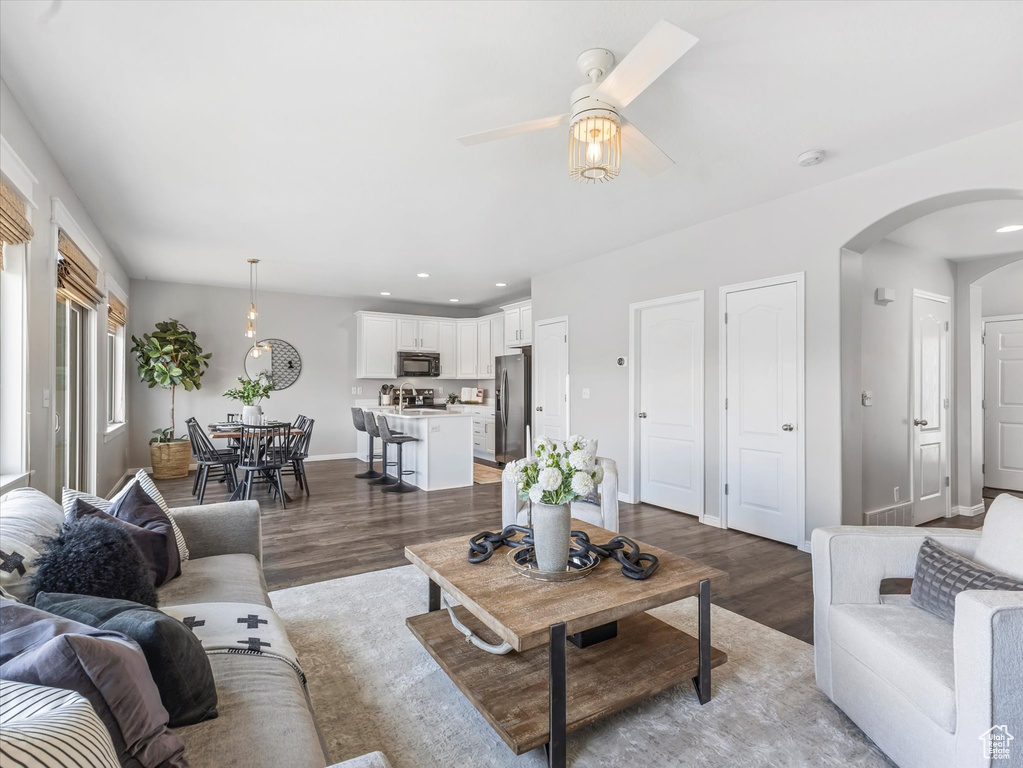 Living area with recessed lighting, arched walkways, wood finished floors, and a ceiling fan