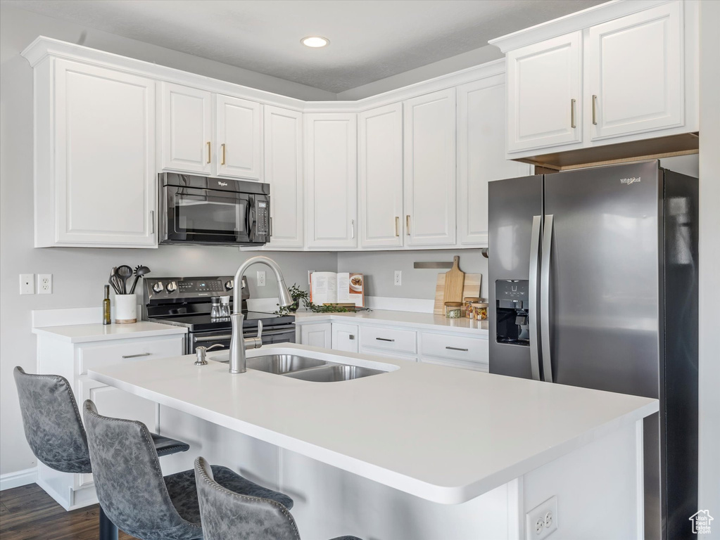 Kitchen with a sink, white cabinets, and stainless steel appliances