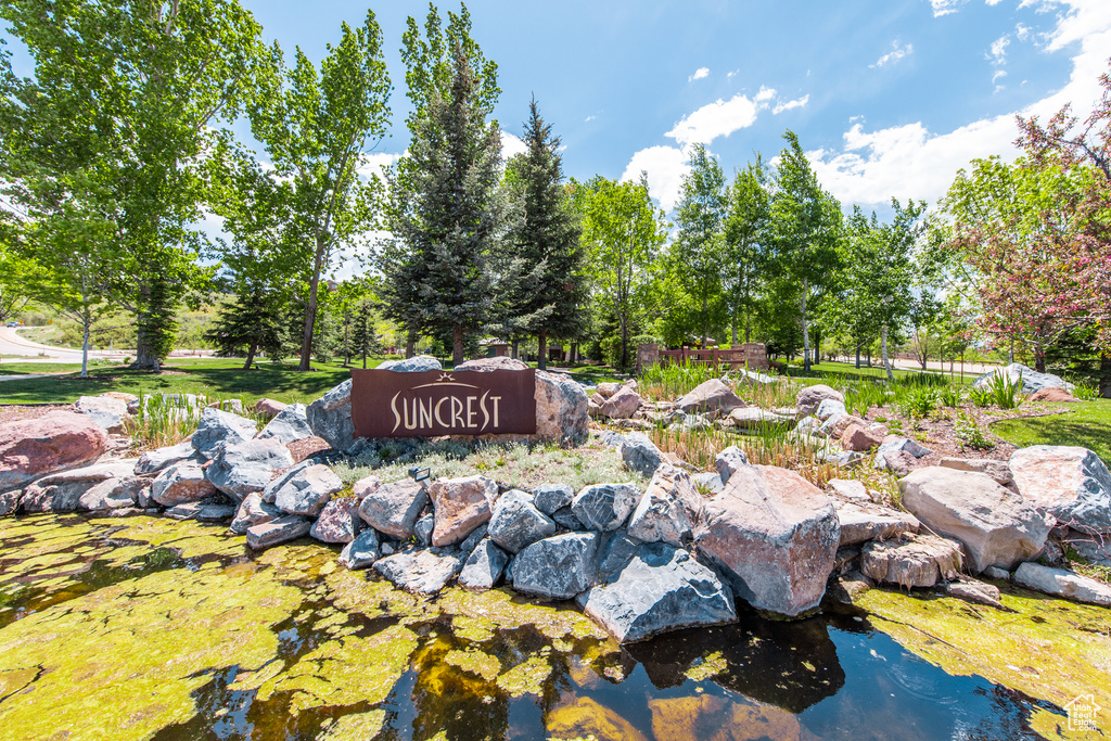 Community / neighborhood sign featuring a small pond