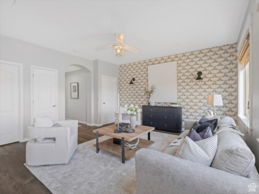 Living area featuring arched walkways, ceiling fan, baseboards, and wood finished floors
