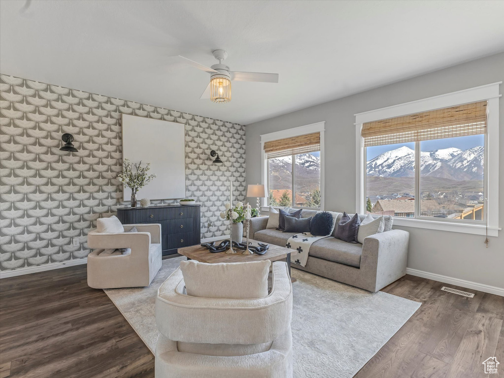 Living area with visible vents, baseboards, a ceiling fan, and wood finished floors