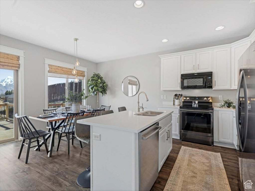Kitchen with a sink, light countertops, appliances with stainless steel finishes, and dark wood finished floors