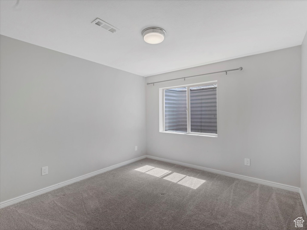 Empty room featuring carpet, visible vents, and baseboards
