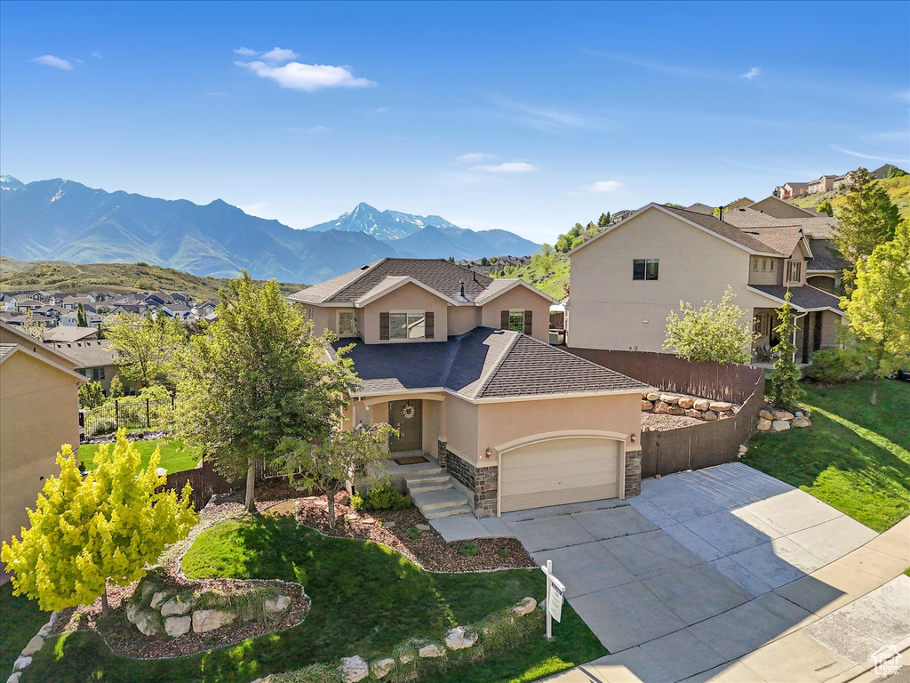 View of front of property featuring stucco siding, an attached garage, stone siding, driveway, and a residential view