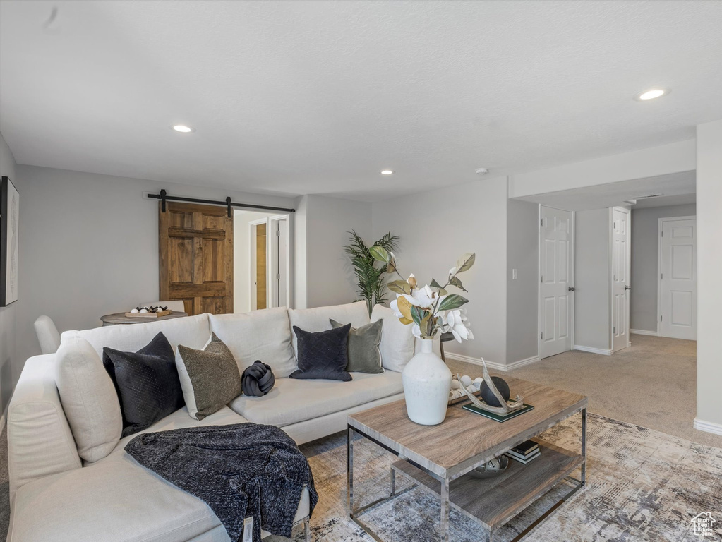 Living area with baseboards, recessed lighting, a barn door, and light carpet