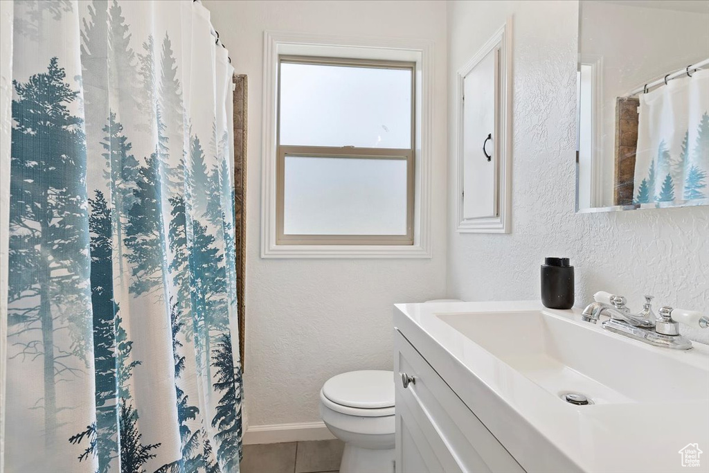Full bath with a textured wall, tile patterned floors, vanity, and toilet