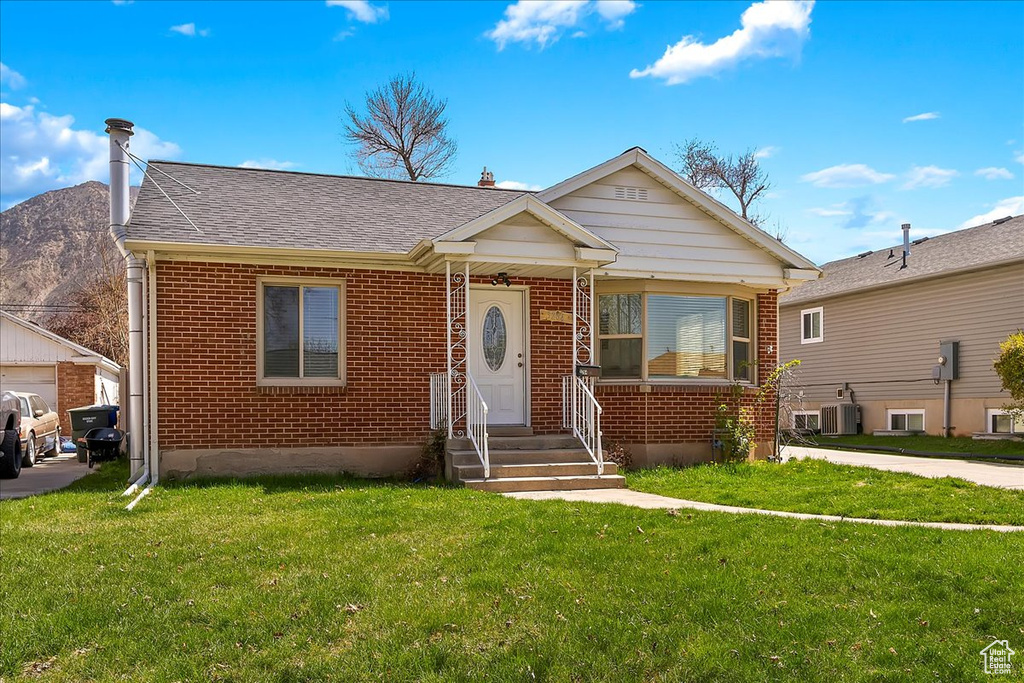Bungalow-style house featuring brick siding, central AC, a mountain view, and a front lawn