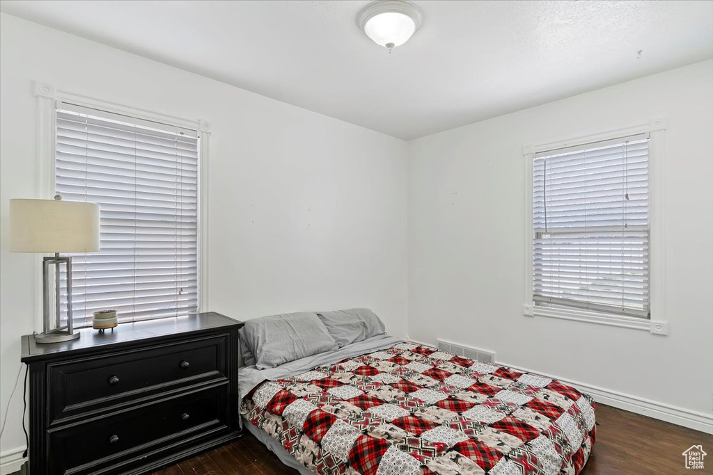 Bedroom with visible vents, baseboards, baseboard heating, and dark wood finished floors