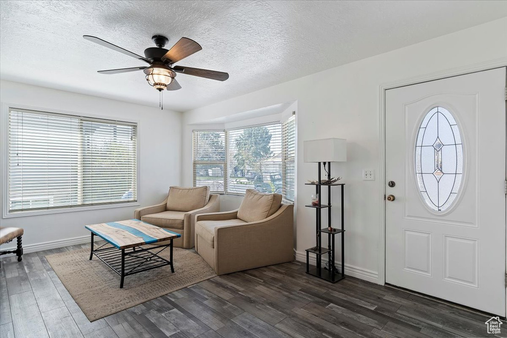 Entrance foyer featuring a textured ceiling, dark wood-style flooring, ceiling fan, and baseboards